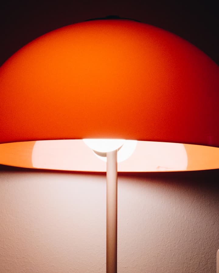 Een lamp met oranje kap in een donkere kamer