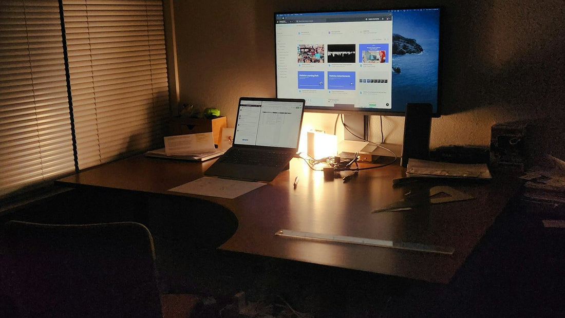 Bureau met laptop en scherm in de avond, warm lampje