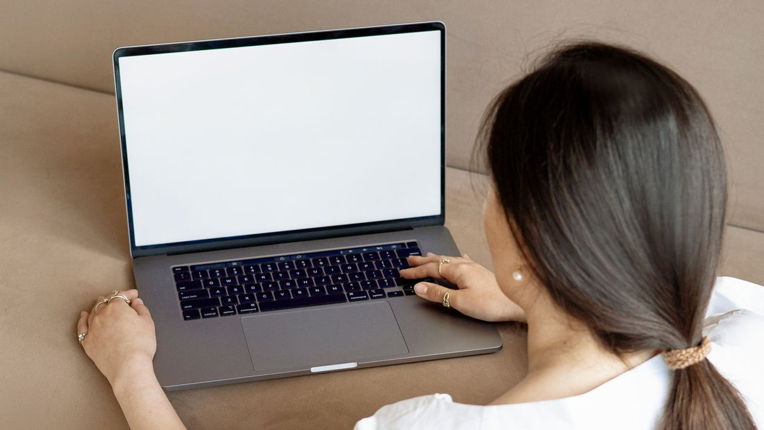 Vrouw van achteren werkt op een laptop op de bank