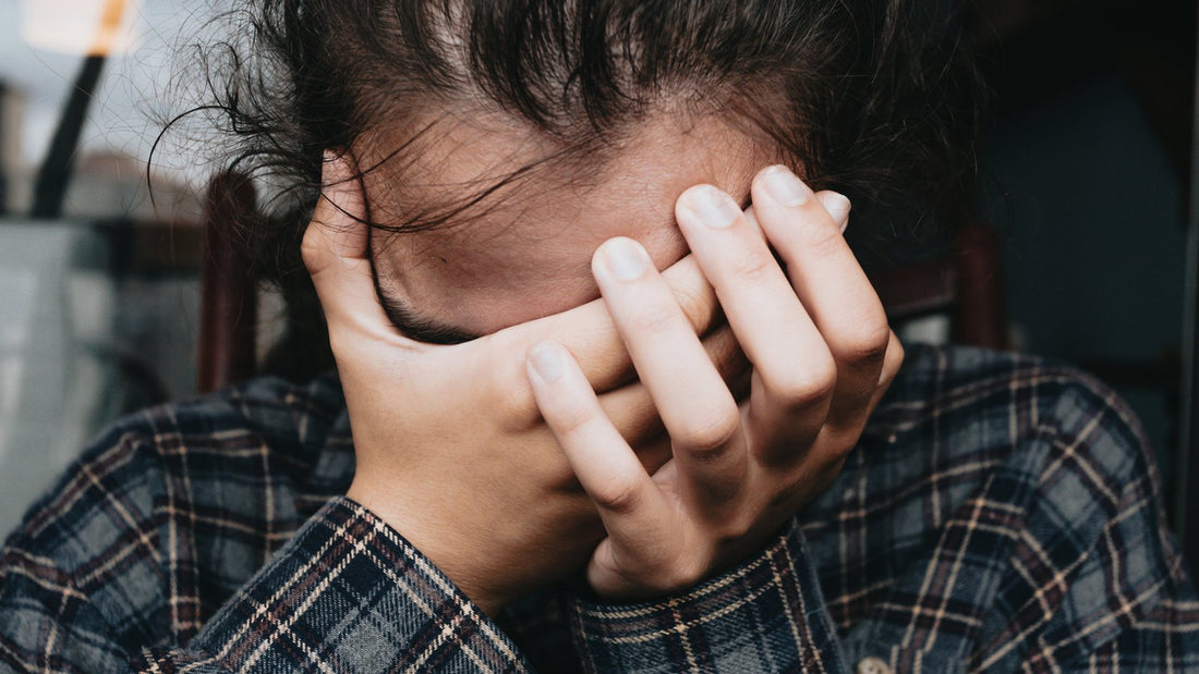 Persoon met handen tegen het voorhoofd