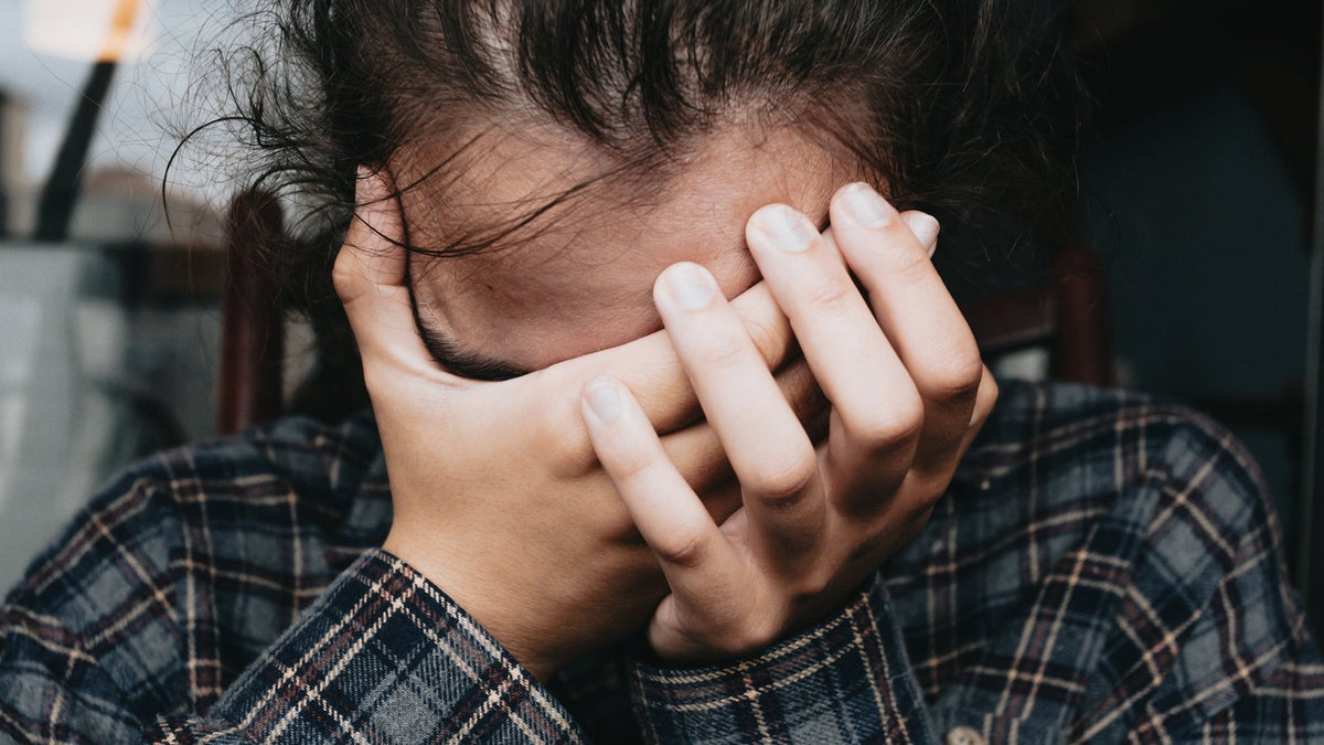 Persoon met handen tegen het voorhoofd