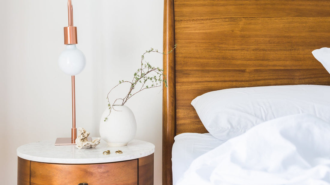 Klein lampje op een houten nachtkastje naast een bed