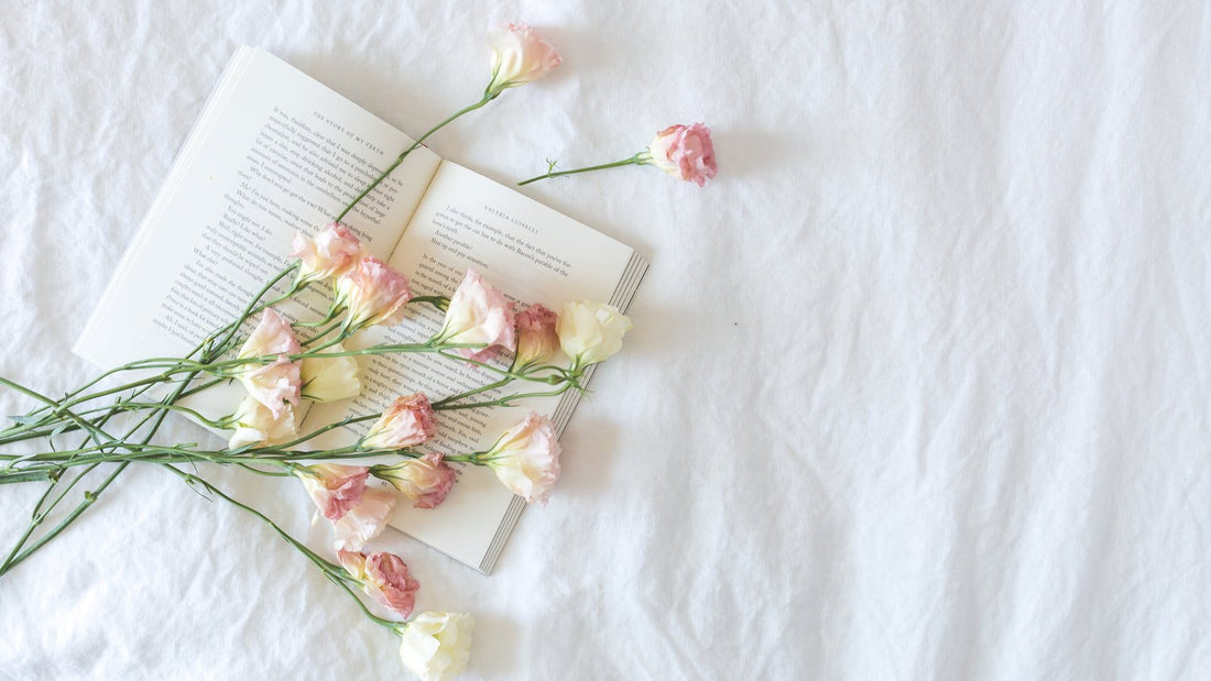 Boek met verse bloemen op wit beddengoed
