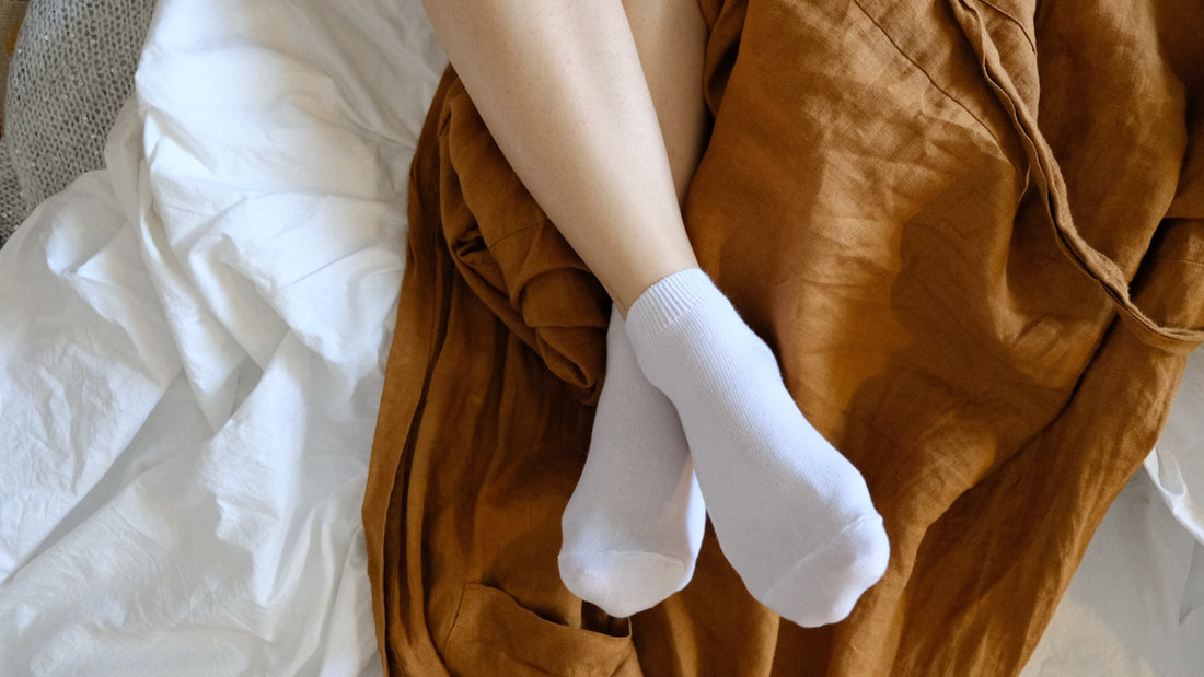 Voeten in warme sokken op een bed met linnen dekens