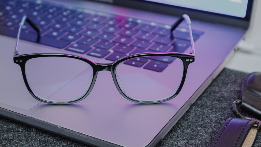 Bril op een laptoptoetsenbord met blauwpaars schermlicht