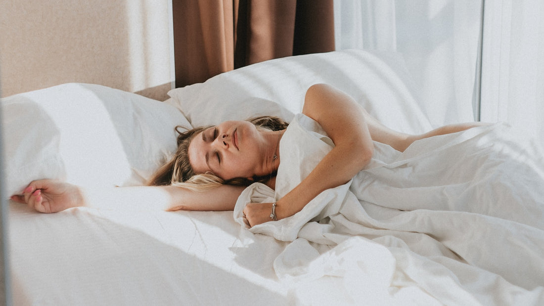Vrouw ligt wakker in bed in een lichte slaapkamer