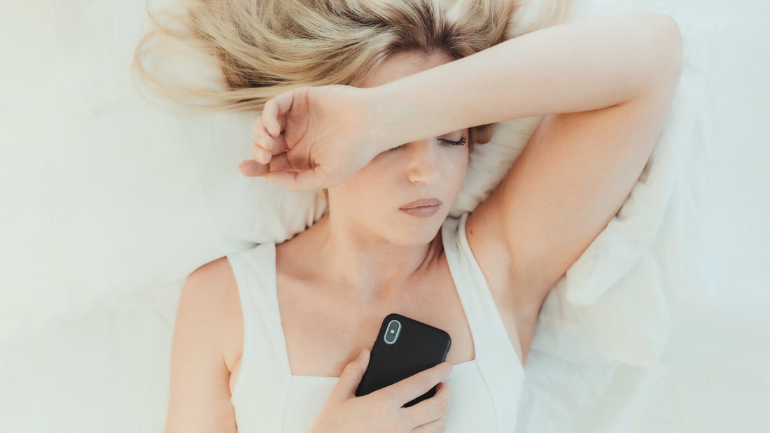 Vrouw ligt wakker in bed met haar telefoon in haar hand