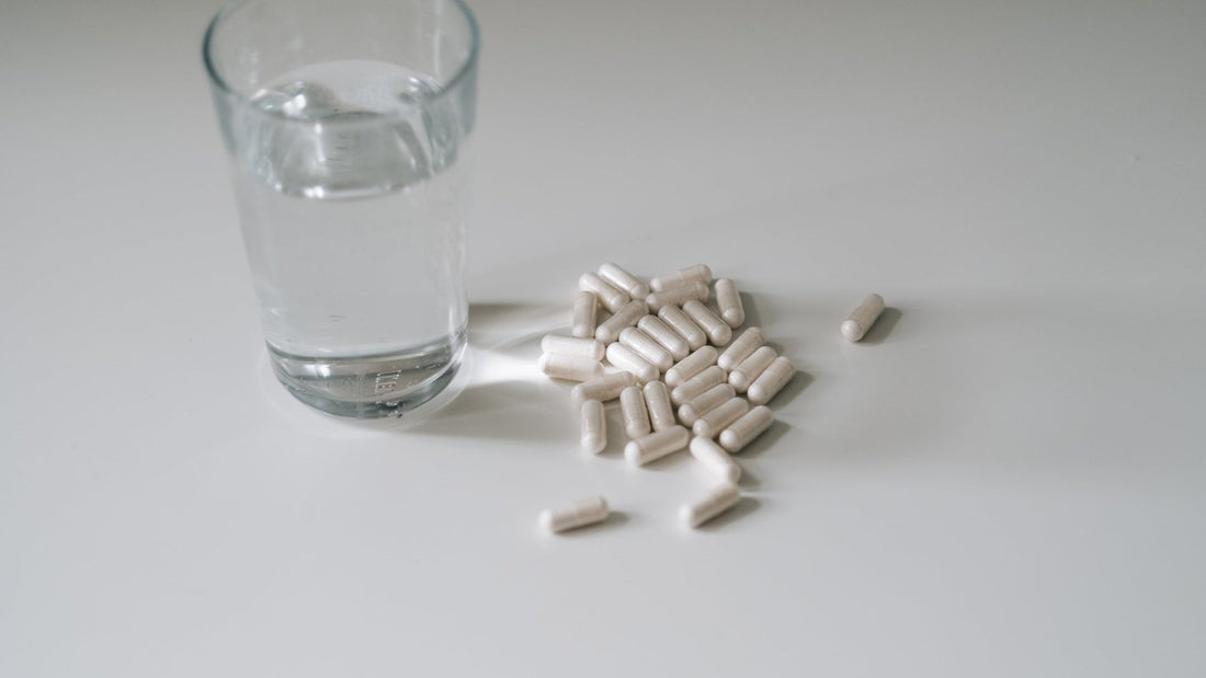 Glas water met capsules ernaast op een licht oppervlak