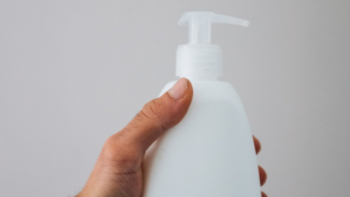 Hand houdt een wit sprayflesje vast