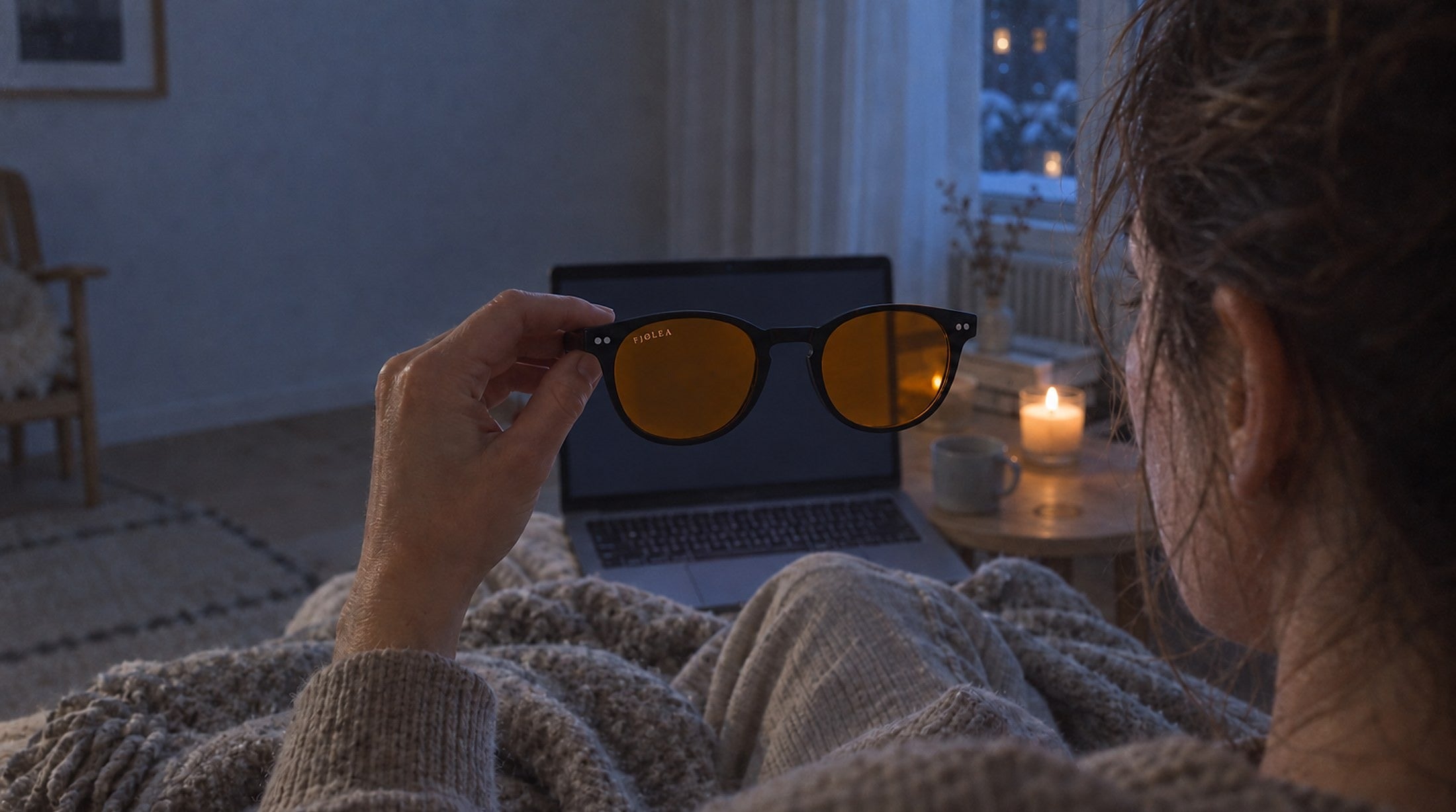 Vrouw kijkt 's avonds door de Fjølea Måne naar haar laptop